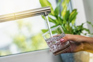 woman hand holds a glass to Filing it with water from tap