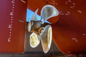 Cargo vessel in dry dock on ship repairing yard. Variable pitch propeller and rudder.
