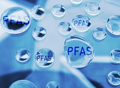 Clear water droplets labeled 'PFAS' on a blue surface.
